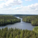 Maisemakuvan etualalla on tyyni lampi. Se takana kohoaa jyrkkä kallionseinämä, jonka laella kasvaa metsää. Sää on hieman harmaa ja syksyinen ja ilmassa on utua. Kuva: Mari Laukkanen