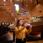 A lady taking a picture of boats inside the Boat hall.