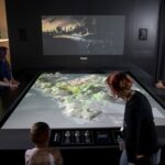 Adults and kids playing with a 3D model of a city map.