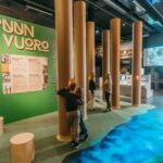 Two boys peaking into a hole, two women on the background.