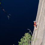 Kiipeilijä nousemassa Olhavan kiipeilykalliolla lammen yläpuolella.