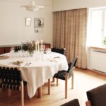 Private dinner table is set in Kantola. There is white tablecloth and some candles and flowers.