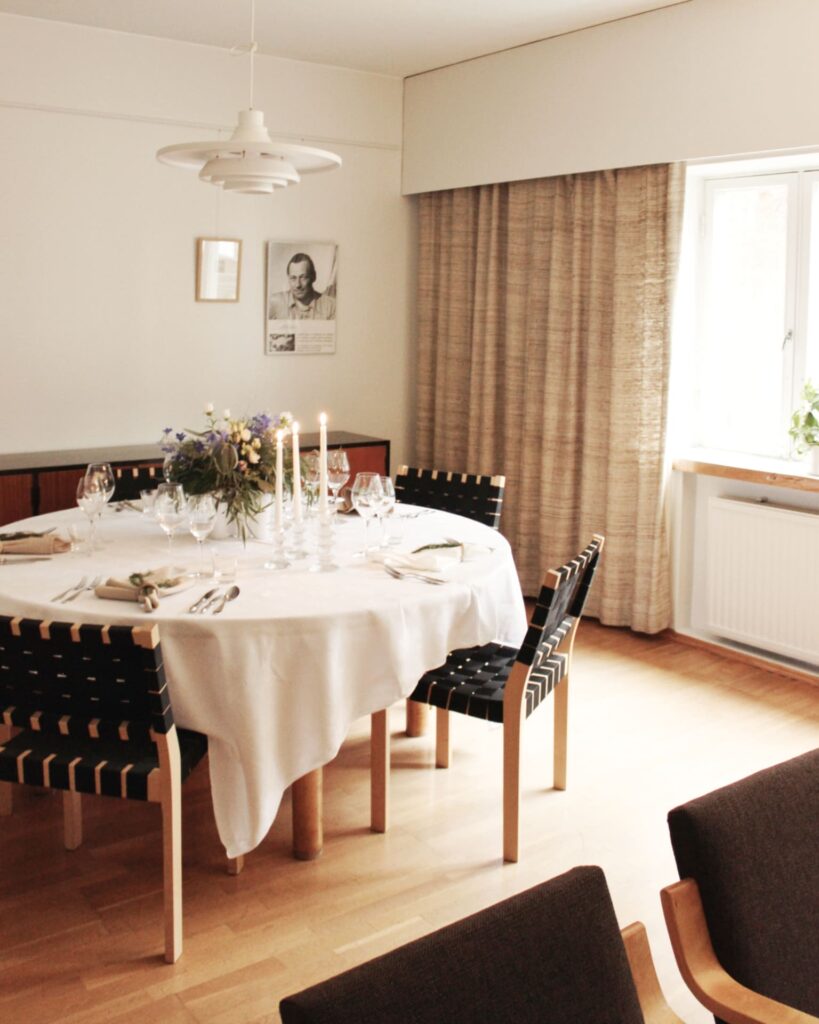 Private dinner table is set in Kantola. There is white tablecloth and some candles and flowers.