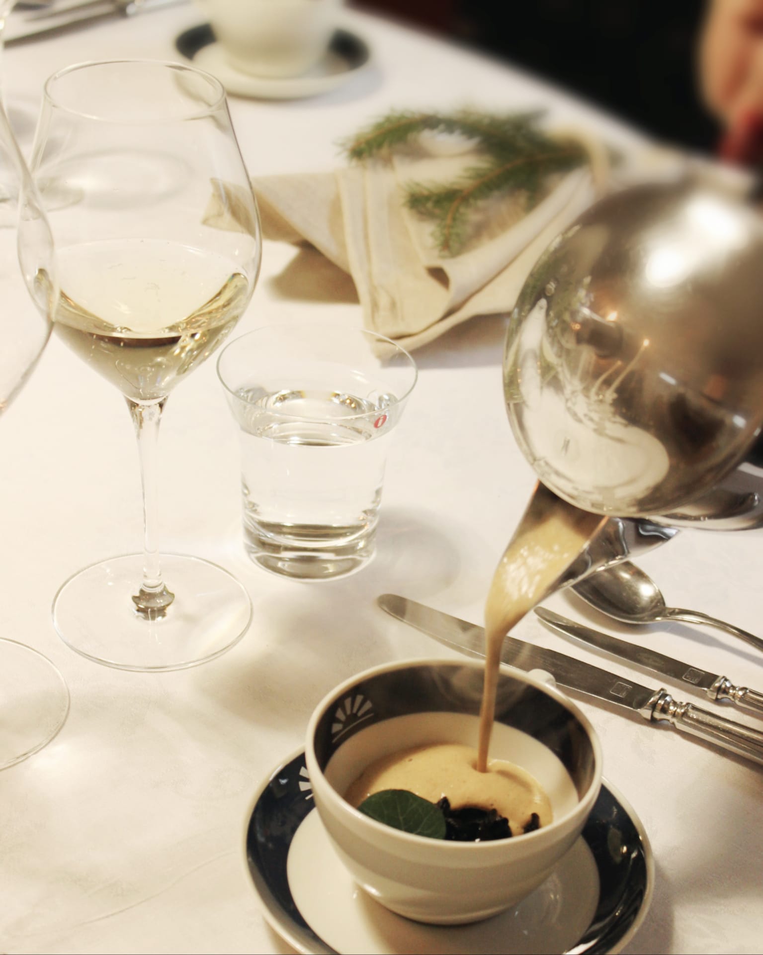 The waiter pours the mushroom soup into a cup.