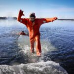 A person jumping from an ice raft to a another in a survival suit.